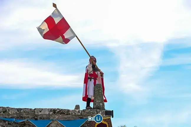 Un integrante del bando cristiano ondea su bandera desde lo alto de la torre del castillo tras recuperarla de los moros en el domingo da Sa&iacute;nza. | Foto: Noelia Caseiro.