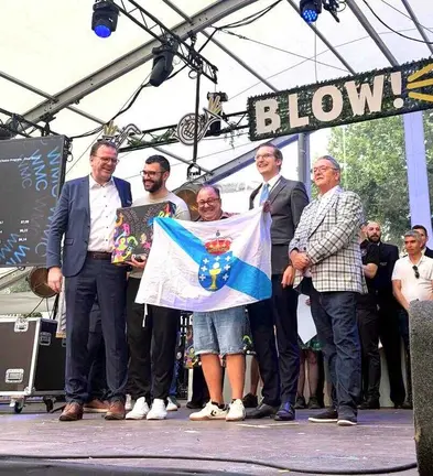 Jos&eacute; Luis Tielas, director de la Agrupaci&oacute;n, con la bandera gallega en el momento de recoger la medalla de oro.