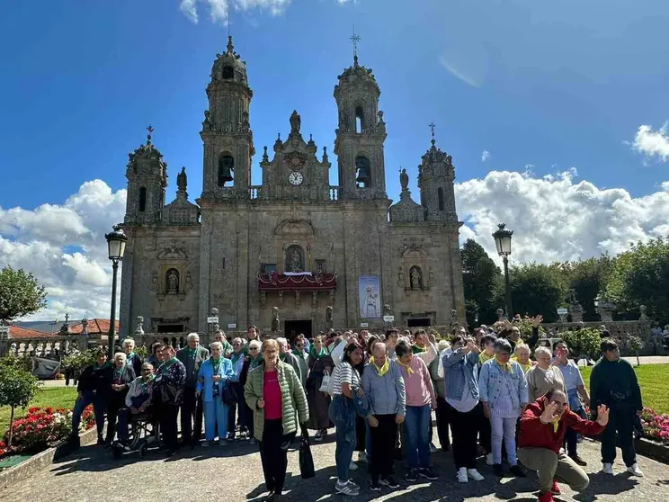 Dos grupos de usuarios posan delante del santuario de Los Milagros.