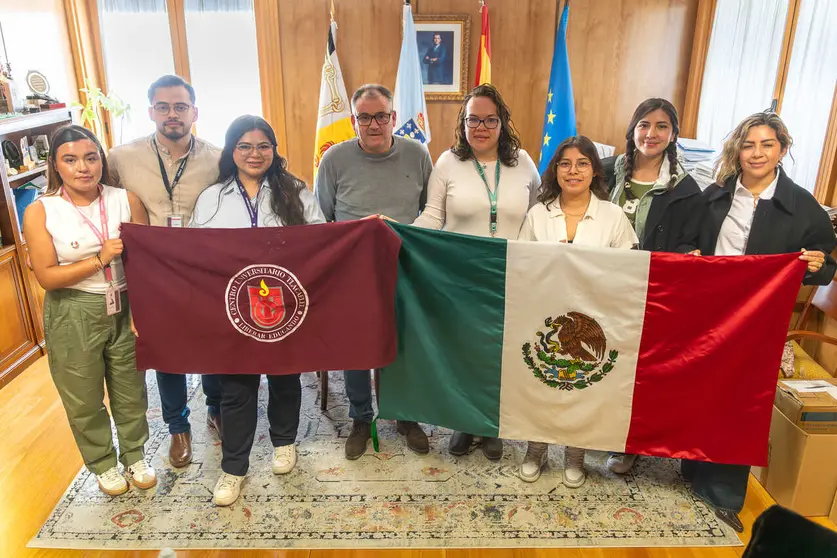 El alcalde Amador D&iacute;az protagoniza una foto de familia junto a la delegaci&oacute;n de estudiantes, quienes portaban las banderas de M&eacute;xico y su universidad durante su recepci&oacute;n.