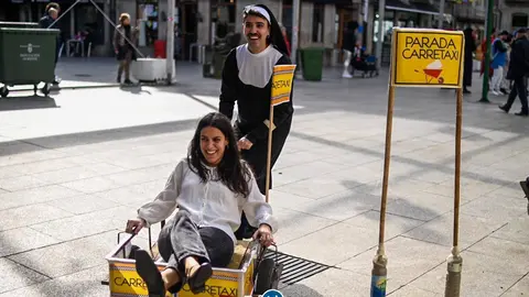 Una electora, transportada a su mesa en el nuevo servicio de esta divertida congregaci&oacute;n de religiosos: el "Carretaxi". | FOTO: Noelia Caseiro.