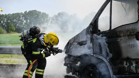 Un bombero del cuerpo de Xinzo de Limia sofocando las llamas del veh&iacute;culo. | Foto: Noelia Caseiro.